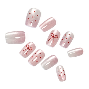 Pink pearlescent press-on nails set featuring red polka dots and bow designs