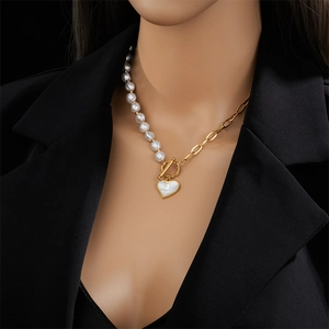 Collier en acier titane avec perles et pendentif cœur doré sur fond de blazer noir