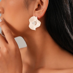 Close-up of ivory flower earrings with square crystal detail worn by a model