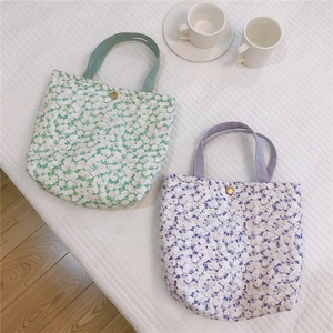 Détail de sacs à lunch en coton fleuri, vert et violet, avec boutons-pression en métal