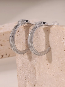 Détail macro de boucles d'oreilles serpent en argent avec écailles et yeux noirs