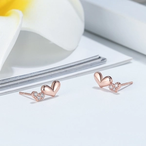 Macro shot of rose gold double heart earrings with crystal pavé and floral accents
