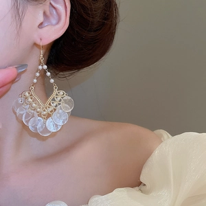 Detail of bohemian shell tassel earrings with white pearls and iridescent round discs