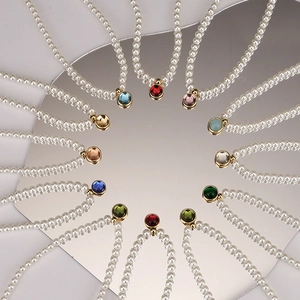 Golden pearl necklaces featuring vibrant round birthstone pendants on a mirror base