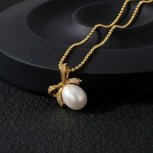 Elegant gold bow necklace with sparkling crystals and a white freshwater pearl pendant