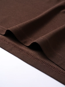 Detailed close-up of dark brown waffle knit fabric texture and double-needle stitching