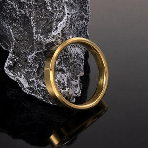 Polished 6mm golden titanium steel ring resting on a textured black mineral stone