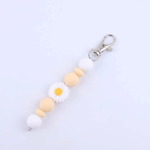 Close-up of white daisy charm with silicone beads on a metal keychain strap