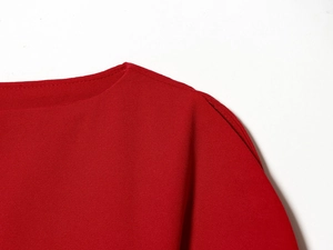 Vue détaillée du col et de la texture du tissu rouge sur l'épaule du haut