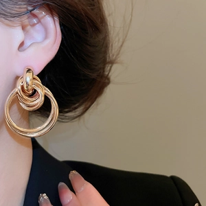 Close-up of gold interlocking hoop earrings worn for an elegant and layered metallic style