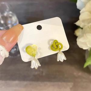 Detail of lily of the valley earrings with green matte knot and white floral petal drop