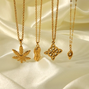 Detail of four gold stainless steel necklaces with various charms on silk fabric