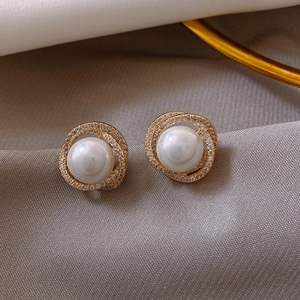 Close-up of elegant gold-plated pearl earring with micro-set zircons on grey silk
