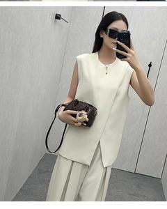 Detail of a minimalist cream-white sleeveless vest and wide-leg trousers suit set