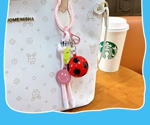Detail of a soccer ball keychain with colorful charms attached to a white tote bag