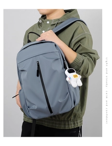 Detail view of the water-resistant blue-gray backpack with astronaut pendant on a model