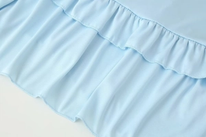 Detail of light blue layered ruffles with fine micro-mesh texture on a soft knit fabric
