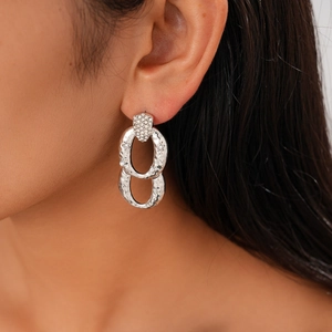 Detail of silver geometric hoop earring with hammered texture and sparkling crystals