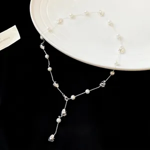 Irregular pearl and hematite Y-shaped beaded necklace on a white porcelain plate