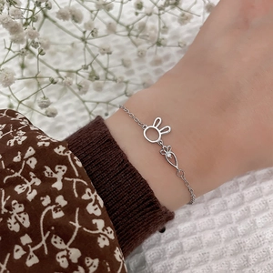 Detailed view of silver rabbit and crystal carrot charms on a delicate charm bracelet