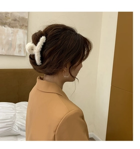 Detailansicht einer weißen Plüsch-Haarklammer, die von einem Model im Haar getragen wird