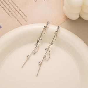 Macro view of long silver leaf tassel earrings with clear cubic zirconia on a tray