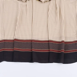 Close-up of beige chiffon maxi dress with red and black geometric prints and fine stitching