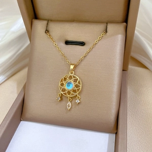 Macro detail of a gold dreamcatcher necklace with blue gemstone and sparkling crystals