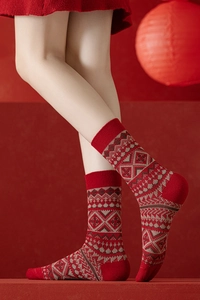 Détail de chaussettes en laine rouge avec motifs de flocons nordiques et revers côtelés