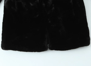 Gros plan sur l'ourlet en fausse fourrure pelucheuse de la veste noire élégante