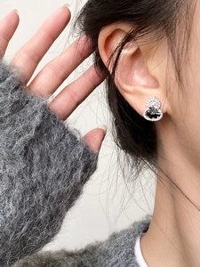 Macro shot of silver zircon gourd earrings with black and white stone inlays on a model