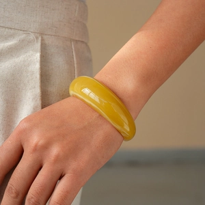 Close-up of translucent amber acrylic open cuff bracelet on female model wrist
