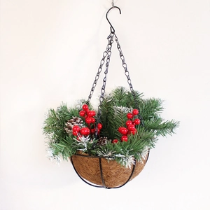 Hängender Weihnachtskorb mit schneebedeckten Kiefernnadeln, roten Beeren und Zapfen