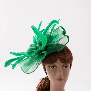 Detail of emerald green feather fascinator with mesh netting on a white background