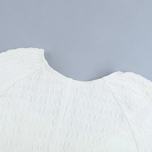 Detail shot of the white textured fabric and ruffled neckline of the mini dress