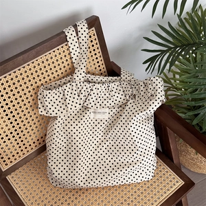 Detailed texture of polka dot canvas tote bag with ruffle trim on a vintage chair