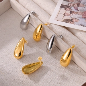 Polished gold and silver teardrop earrings in a textured jewelry box with photo