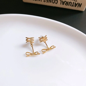 Detail of elegant gold bowknot earrings on a ceramic dish with metallic finish
