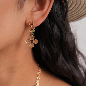 Detail of vintage gold cross earrings with reddish-brown gems and sparkling rhinestones