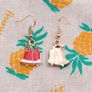 Close-up of red and white enamel Christmas bell earrings with golden bow details
