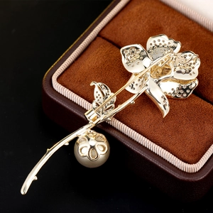 Close-up of a luxury flower brooch with gold plating, sparkling zircons and a pearl detail