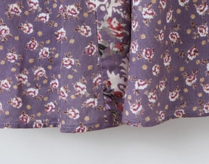 Gros plan de l'ourlet d'une robe vintage violette fleurie en mousseline fine