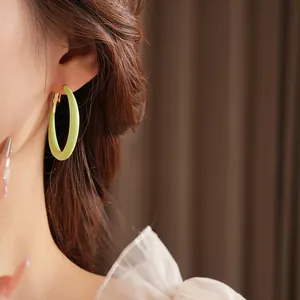 Lime green minimalist large hoop earrings on model with high quality silver pin clasp