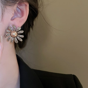 Detail of golden sunflower earrings with pearl centers and diamond petal accents