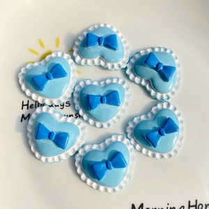 Detailed view of blue heart-shaped DIY resin charms with 3D bowknot for phone case crafts