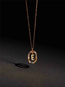 Detail of gold letter E pendant featuring a halo of vibrant multi-color cubic zirconia
