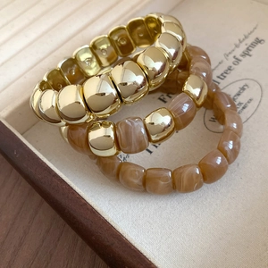 Detail of three-piece amber resin and gold bead stretch bracelet set in a jewelry box