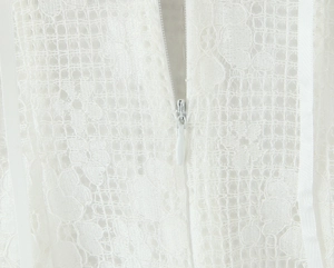 Détail du tissu en dentelle blanche avec fermeture éclair cachée sur une robe courte