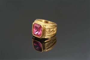 Detail of golden dragon ring featuring a large pink square gemstone and intricate relief