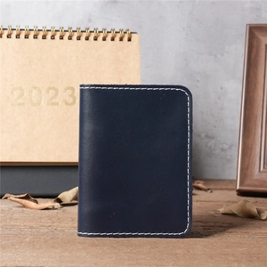 Close-up of vintage dark blue leather wallet with white stitching on wooden desk